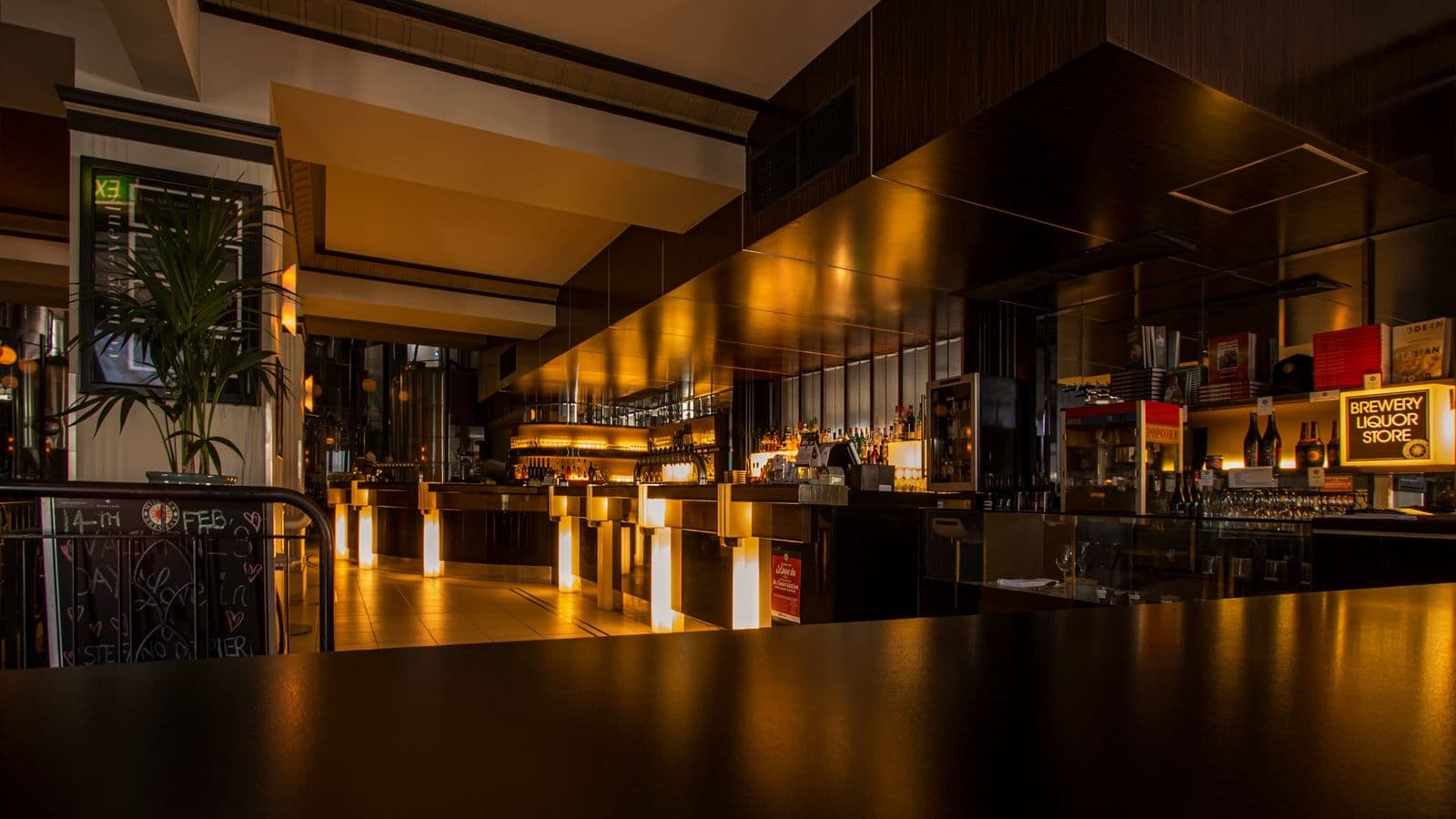 Warmly lit restaurant bar at night with golden lighting along the counter